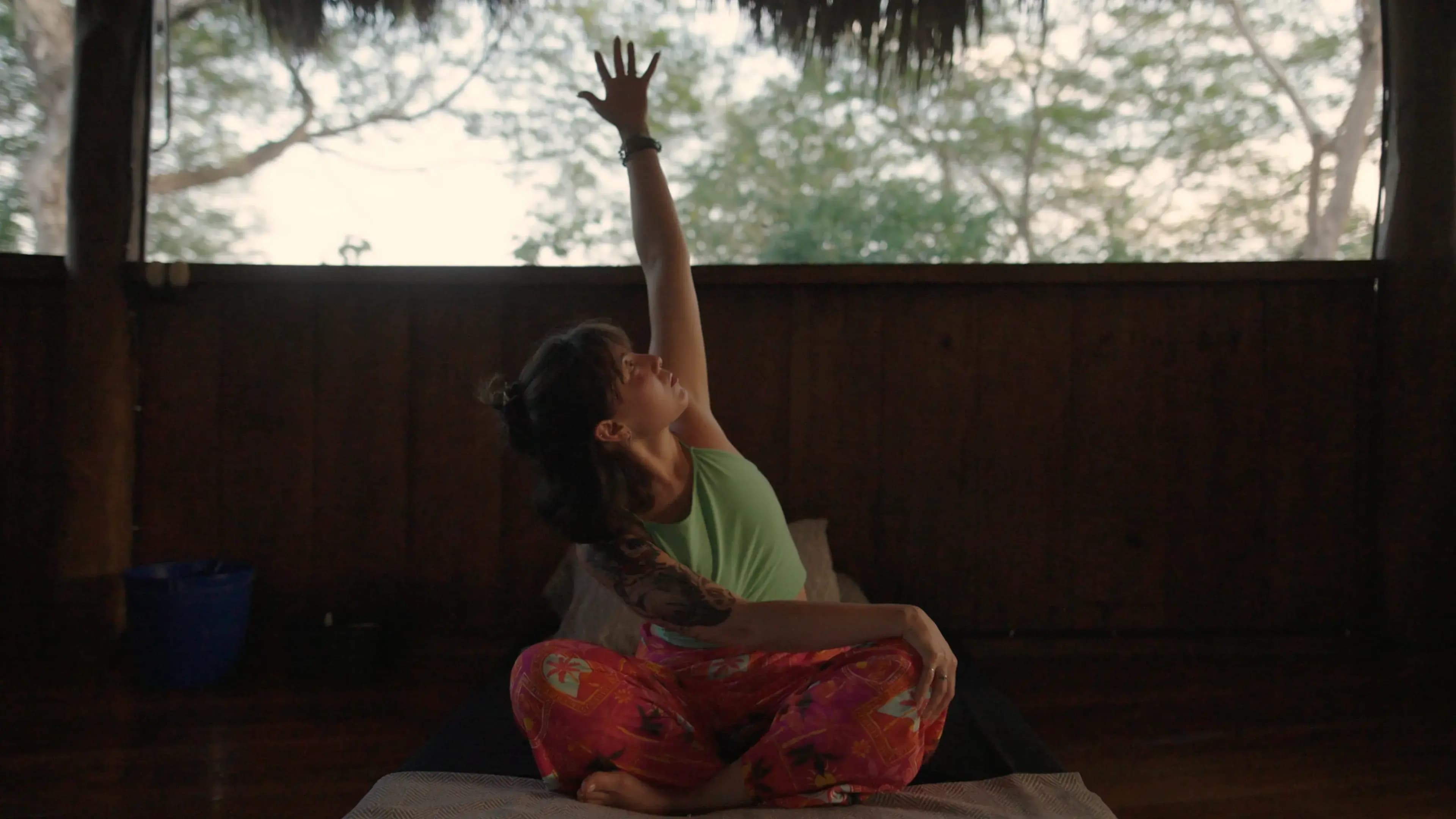 A guest raising her hand while seated in a maloca.