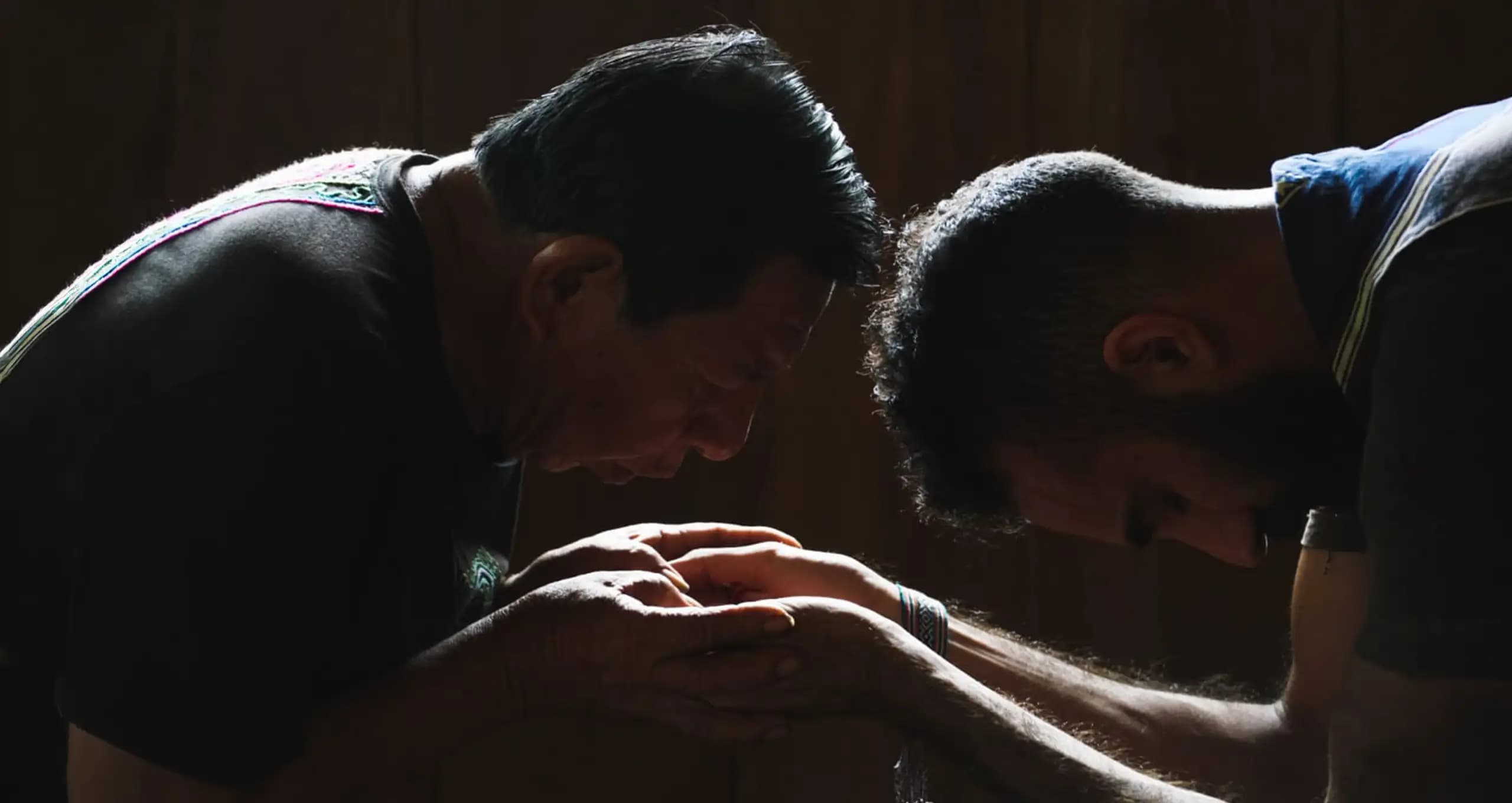 A healer holding a guest's hands during ceremony.
