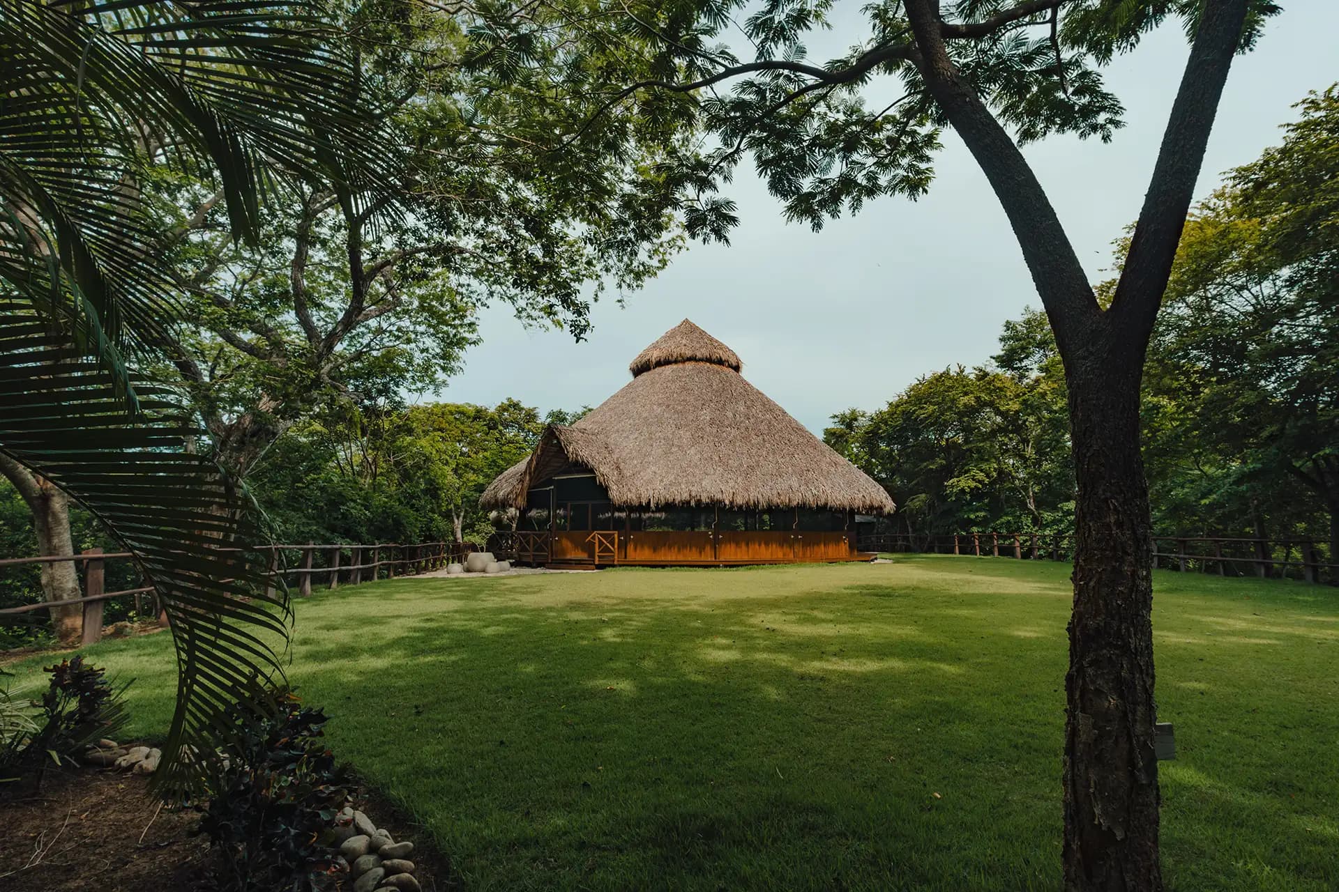 Thatched retreat building surrounded by tropical trees and lawn